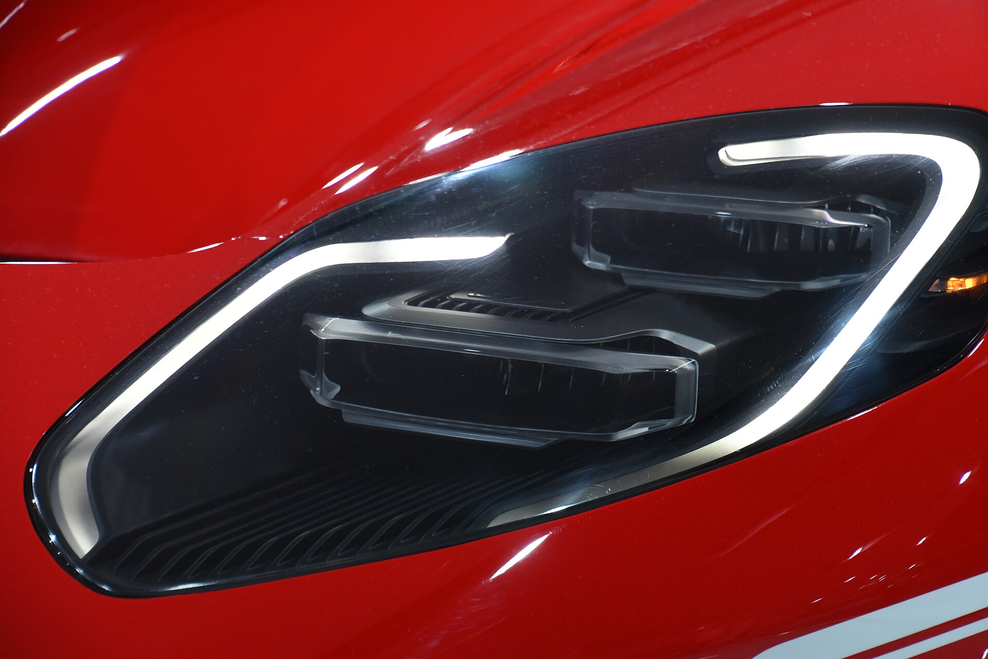 Macro of the GT's headlamp: a lit signature strip wrapped around twin projector bricks